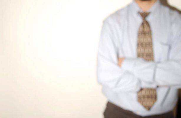 Businessman in shirt and tie with crossed arms standing against.jpg