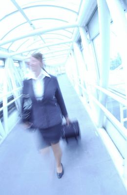 Businesswoman pulling suitcase through glass hallway.jpg