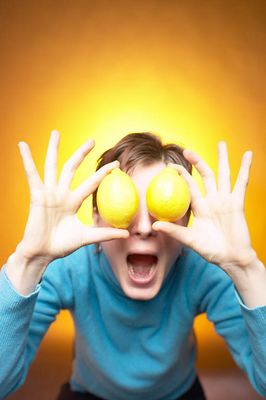 Caucasian woman holding yellow lemons to eyes against yellow bac 1.jpg