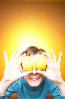 Caucasian woman holding yellow lemons to eyes against yellow bac 2.jpg