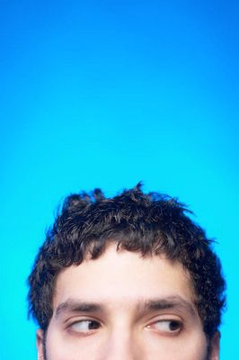 Hispanic man looking sideways against blue background.jpg