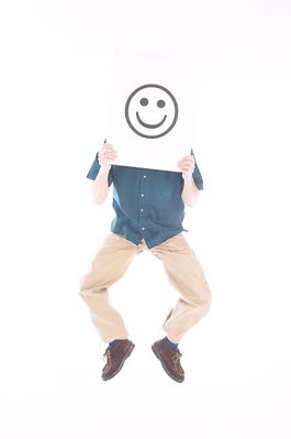 Man jumping while holding smiling face sign over his face.jpg