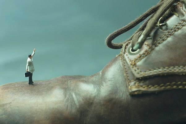 Model of businessman standing on leather shoe.jpg