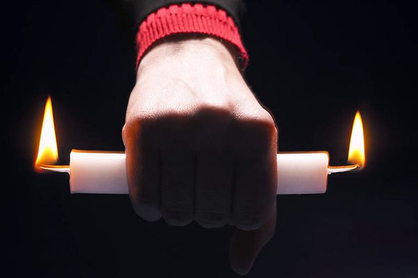 Person holding candle burning at both ends 1.jpg