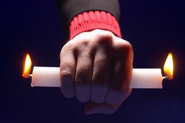 Person holding candle burning at both ends.jpg