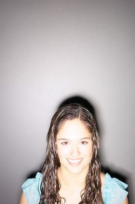 Smiling teenaged girl standing against gray wall 1.jpg