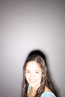 Smiling teenaged girl standing against gray wall 2.jpg