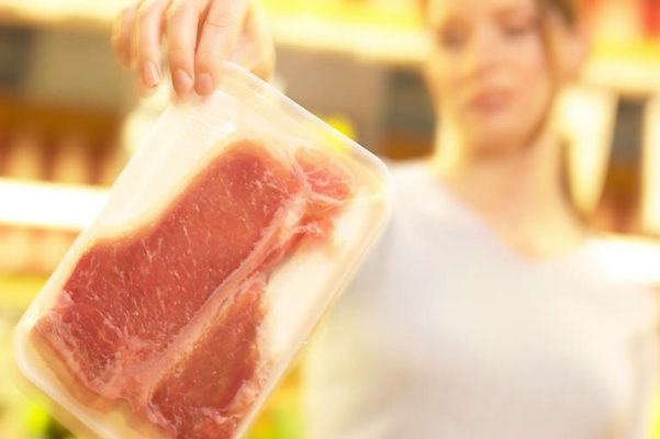 Woman gingerly holding up package of meat an 1.jpg