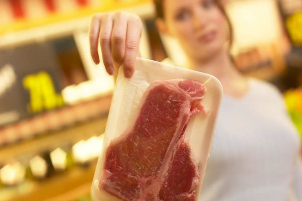 Woman gingerly holding up package of meat an 2.jpg