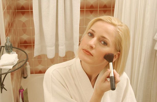 Woman putting on makeup in bathroom mirror.jpg