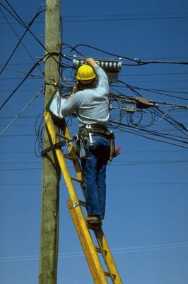 Worker fixing telephone wires on pole.jpg