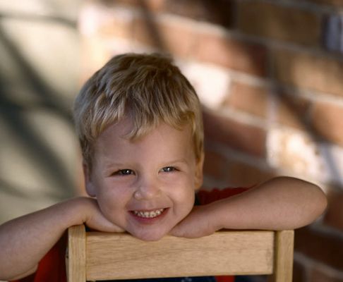 Young boy sitting backwards on a chair and smiling.jpg