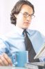 Businessman reading newspaper at his desk 100.jpg