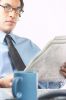 Businessman reading newspaper beside mug of coffee 1.jpg