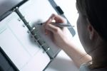 Caucasian businesswoman writing in day planner with pen 1.jpg