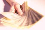 Caucasian man holding spread of American bills.jpg