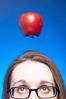 Caucasian woman face with glasses with apple hanging over her.jpg