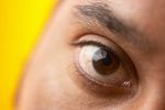 Close up of South Asian man brown eye against yellow backgroun.jpg