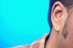 Close up of South Asian man ear against blue background.jpg