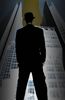 Man in suit and bowler hat standing in front of skyscraper.jpg