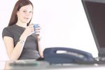Smiling woman drinking coffee at her desk.jpg