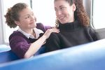 Two smiling women sitting in blue vinyl seats uid 1283664.jpg