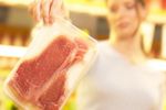 Woman gingerly holding up package of meat an 1.jpg