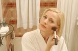Woman putting on makeup in bathroom mirror.jpg