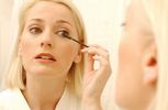 Woman putting on mascara in bathroom mirror.jpg