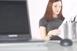 Woman reading newspaper at her desk c103113.jpg